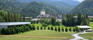 Ein Polizeiauto fährt die Straße von Schloss Elmau herunter, links ist der Pressebereich und rechts die Pressetribüne zu sehen. 