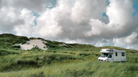Ein Wohnmobil hat sich in den Dünen eingerichtet.
