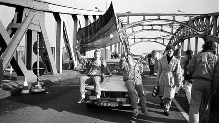 Am Grenzübergang Bornholmer Straße strömen auch am 10. November 1989 Ost-Berliner nach West-Berlin. Zwei Ost-Berliner sitzen mit einer Deutschlandfahne auf ihrem Dacia 1300. Bürgerinnen und Bürger aus West-Berlin begrüßen die DDR-Bürger.