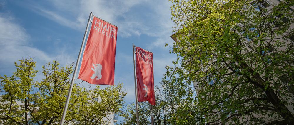 Ein Blick in den Himmel, mit einer Ecke des Hauptgebäudes der HWR Berlin und den Flaggen der Hochschule.