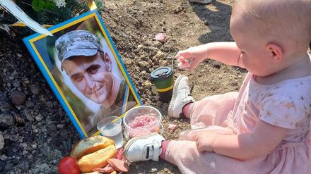 Ein ukrainisches Mädchen frühstückt am Grab seines gefallenen Vaters, das ukrainische Verteidigungsministerium verbreitet das Bild.