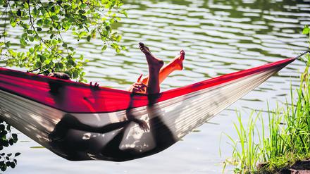 Ein Paar liegt am Ufer des Schlachtensees in einer Hängematte.