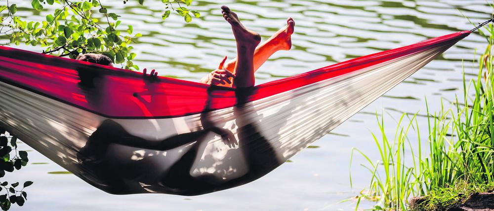 Ein Paar liegt am Ufer des Schlachtensees in einer Hängematte.