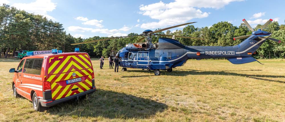 04.07.2022, Brandenburg, Byhlen: Ein Löschhubschrauber der Bundespolizei steht in einer Wartungspause auf einer Wiese. Der Waldbrand in der Lieberoser Heide breitet sich nach Einschätzung des Landkreises aus. Das Feuer in dem mit Munition belasteten Gebiet wurde als «Großschadenslage» eingestuft, wie der Landkreis Dahme-Spreewald mitteilte. Foto: Frank Hammerschmidt/dpa +++ dpa-Bildfunk +++