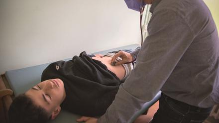 Kinderarzt Jakob Maske hört den Bauch seines Patienten Berat ab.