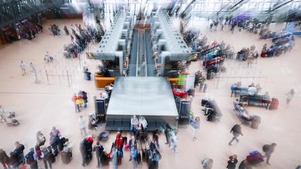 Flugreisende stehen vor den Check-In Schaltern in Terminal 1 am Airport Hamburg. 
