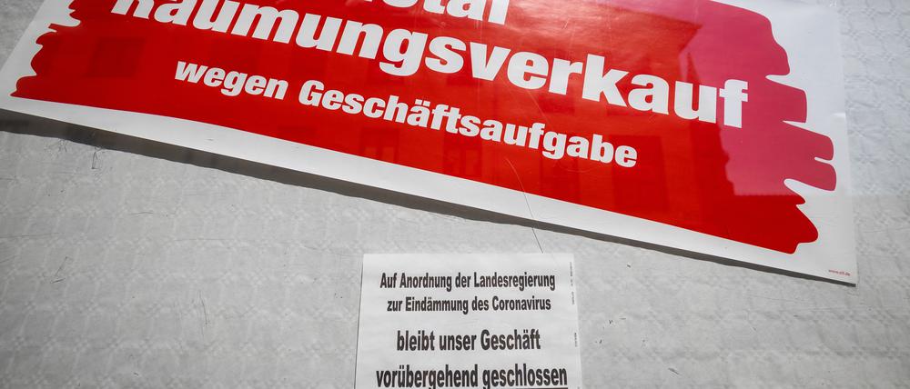 ARCHIV - 16.04.2020, Thüringen, Meiningen: Ein Schild an einem Geschäft weist darauf hin, dass es auf Anordnung der Landesregierung zur Eindämmung des Coronavirus geschlossen ist, darüber hängt ein weiteres Schild mit der Aufschrift «Total-Räumungsverkauf wegen Geschäftsaufgabe». (zu dpa «Lambrecht will Firmensanierung ohne Insolvenzverfahren erleichtern») Foto: Michael Reichel/dpa-Zentralbild/dpa +++ dpa-Bildfunk +++ | Verwendung weltweit