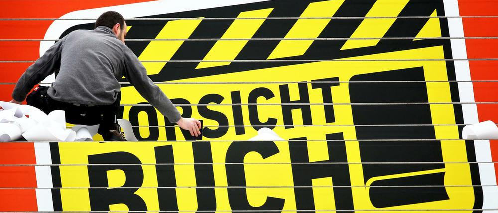 ARCHIV Der Werbetechniker Michael Häßler klebt ein Logo "Vorsicht Buch!" der Leipziger Buchmesse am 10.03.2016 auf eine Treppe in der Glashalle der Leipziger Messe in Leipzig (Sachsen). Zur Buchmesse vom 17. bis 20. März werden rund 2.000 Aussteller und mehr als 250.000 Besucher erwartet. Aus Mecklenburg-Vorpommern nehmen 23 Aussteller teil. Foto: Jan Woitas/dpa (zu: "23 Aussteller aus dem Nordosten auf Leipziger Buchmesse" vom 14.03.2016) +++(c) dpa - Bildfunk+++