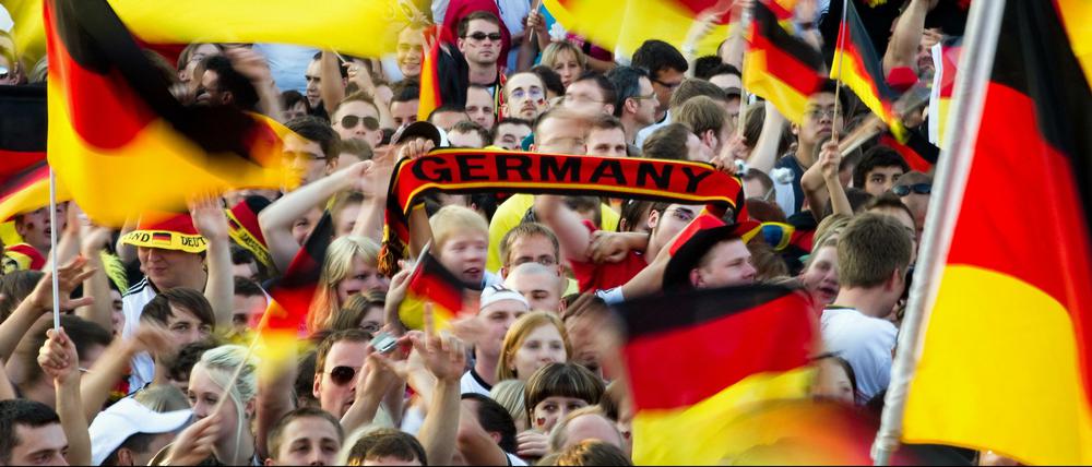 Fußball-WM: Fußballfans feiern beim Public Viewing die deutsche Nationalelf und schwenken Deutschlandfahnen.