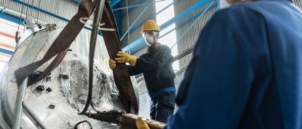 Arbeiter packen ein Maschinenbauteil aus. 