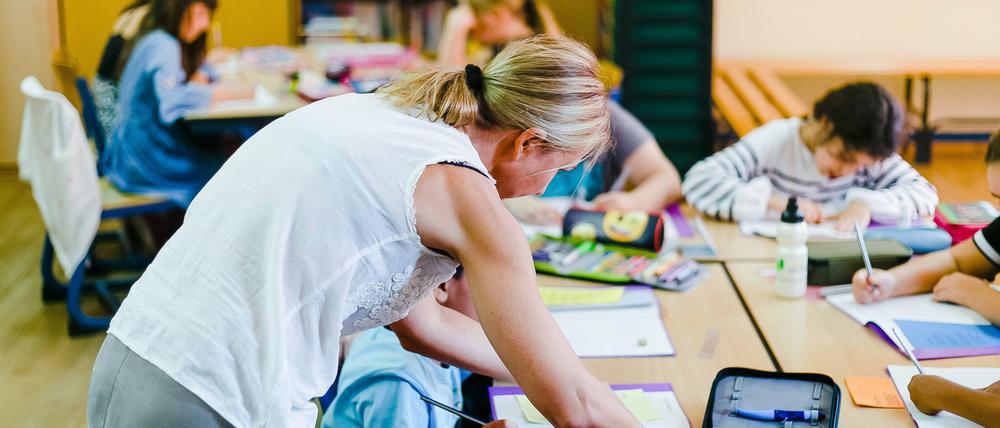 Klassenlehrerin Ulrike Jansen gibt einem Schüler der vierten Klasse einer Grundschule im Deutschunterricht Hilfestellung