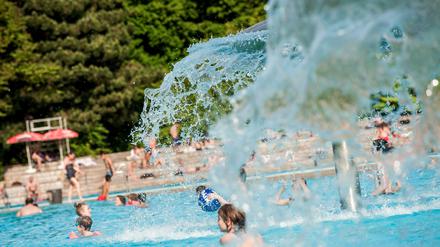 Kinder toben unter dem pilzförmigen Brunnen im Sommerbad Kreuzberg