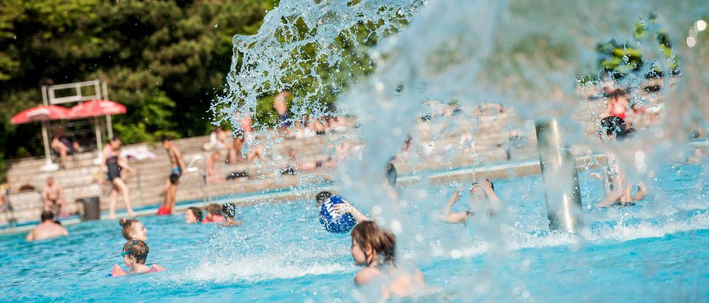 Kinder toben unter dem pilzförmigen Brunnen im Sommerbad Kreuzberg