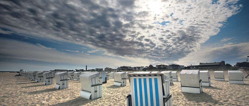 dpatopbilder Über den Strandkörben des Ostseebades Rostock-Warnemünde (Mecklenburg-Vorpommern) kämpft sich die Sonne am 25.08.2015 durch die Wolken. Das hochsommerliche Wetter ist vorerst vorbei. Foto: Bernd Wüstneck/dpa +++(c) dpa - Bildfunk+++