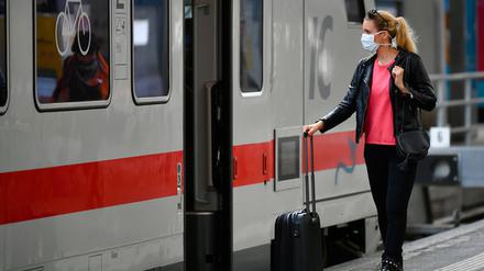 Frau mit Mundschutzmaske wartet auf Zug.
