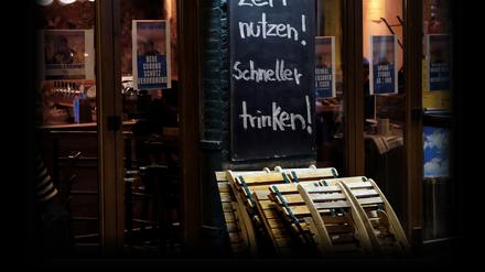 19.10.2020, Nordrhein-Westfalen, Köln: Ein Gastwirt wirbt mit dem Slogan «Zeit nutzen! Schneller trinken!» kurz vor der Sperrstunde vor seinem Lokal. Angesichts steigender Infektionszahlen hatte das Landeskabinett am vergangenen Freitag schärfere Regeln beschlossen. Foto: Oliver Berg/dpa +++ dpa-Bildfunk +++