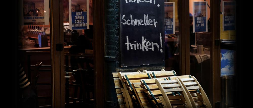 19.10.2020, Nordrhein-Westfalen, Köln: Ein Gastwirt wirbt mit dem Slogan «Zeit nutzen! Schneller trinken!» kurz vor der Sperrstunde vor seinem Lokal. Angesichts steigender Infektionszahlen hatte das Landeskabinett am vergangenen Freitag schärfere Regeln beschlossen. Foto: Oliver Berg/dpa +++ dpa-Bildfunk +++