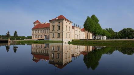 10.05.2022, Brandenburg, Rheinsberg: Die Parkseite von Schloss Rheinsberg spiegelt sich in dem vom Grienericksee gespeisten Wasser des Schlossgrabens. Das der Stiftung Preußische Schlösser und Gärten Berlin-Brandenburg gehörende Schloss kann nach umfangreichen Restaurierungen als Museum besichtigt werden. Foto: Soeren Stache/dpa/ZB - Honorarfrei nur für Bezieher des Dienstes ZB-Funkregio Ost +++ ZB-FUNKREGIO OST +++