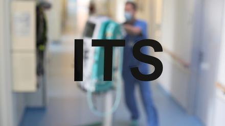 Blick durch eine Glastür auf den Flur vom Intensiv- und Überwachungsbereich einer Klinik. 