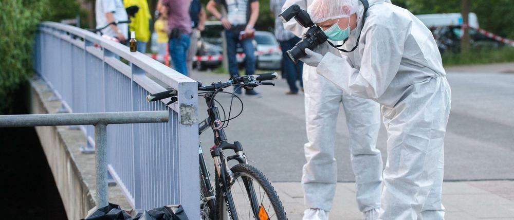 Ein Ermittler der Polizei fotografiert am Sonntag in Hamburg-Bergedorf in der Nähe des Allermöher Badesees am Tatort ein Fahrrad. 