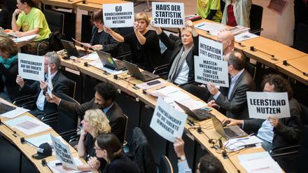 Abgeordnete der Grünen hielten während der Aktuellen Stunde zur Flüchtlingssituation Schilder zum Protest gegen die vom Senat geplante Randbebauung des Tempelhofer Feldes hoch.