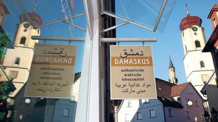 Nahrung für die Seele. Arabisches Lebensmittelgeschäft und katholische Stadtkirche in Sigmaringen, Baden-Württemberg.