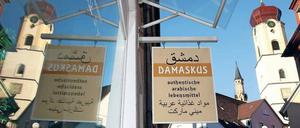 Nahrung für die Seele. Arabisches Lebensmittelgeschäft und katholische Stadtkirche in Sigmaringen, Baden-Württemberg. 