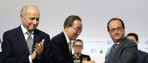 Zwei Präsidenten und ein UN-Generalsekretär. Ban Ki Moon (mitte) freut sich mit Frankreichs Präsidenten Francois Hollande (rechts) über den Abschluss des Pariser Klimavertrags. Links steht der Präsident des Klimagipfels, Außenminister Laurent Fabius. 