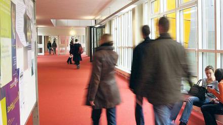 Studierende gehen durch einen Gang in einem Universitätsgebäude.