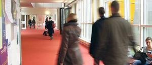 Studierende gehen durch einen Gang in einem Universitätsgebäude.