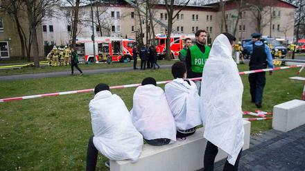 Erneut heimatlos. Nach dem Feuer in einem Flüchtlingsheim in Berlin-Lichterfelde sitzen die Bewohner auf der Straße. Die Brandursache wird noch ermittelt.