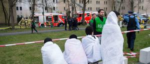 Erneut heimatlos. Nach dem Feuer in einem Flüchtlingsheim in Berlin-Lichterfelde sitzen die Bewohner auf der Straße. Die Brandursache wird noch ermittelt.