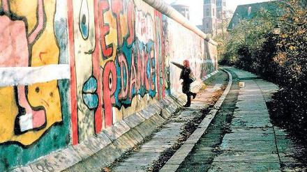 Antifaschistischer Schutzwall, Ghettomarkierung, Bildfläche. Die Mauer in den achtziger Jahren von der Kreuzberger Seite - und eine Aktionskünstlerin bei der Arbeit. Foto: Salzgeber