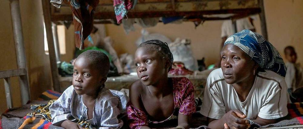Rose Zeeharrah (r), liegt am 16.03.2015 in einem Flüchtlingscamp im Nordosten Nigerias neben ihren Kindern auf einem Bett. Bei einem Angriff der Boko-Haram-Rebellen verlor sie ihren Ehemann. 