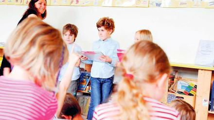 Eine Lehrerin verteilt Zeugnisse in einer Grundschulklasse.