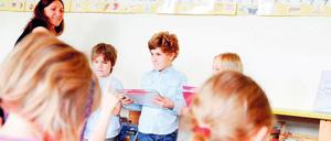 Eine Lehrerin verteilt Zeugnisse in einer Grundschulklasse.