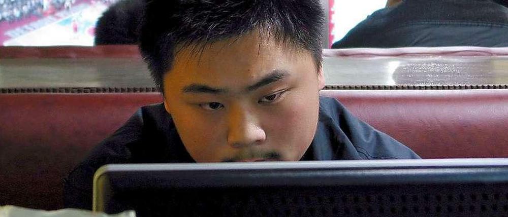 Ein Mann sitzt in einem Internet-Cafe in Qingdao in China an einem Computer.