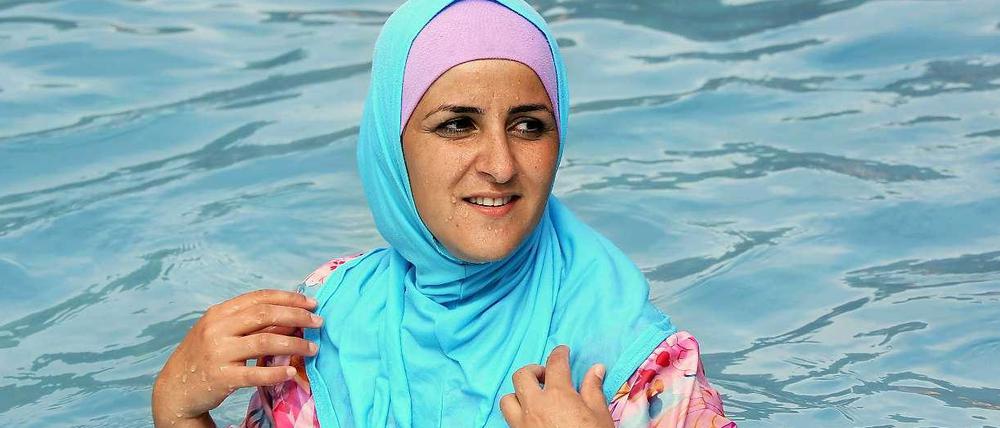 Im Burkini kühlt sich die Berlinerin Abir in einem Freibad in Berlin.