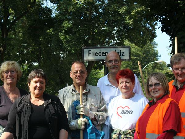 Awo-Freiwillige vor dem Friedensplatz-Straßenschild