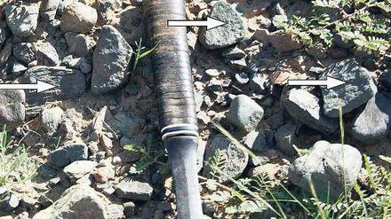 Ein Geologenhammer und halbierte Kiesel liegen auf dem Erdboden.