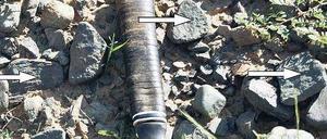 Ein Geologenhammer und halbierte Kiesel liegen auf dem Erdboden.