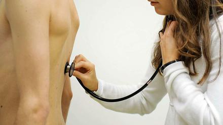 Eine Medizinstudentin hört einen Patienten ab.