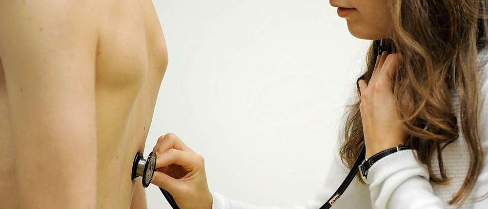 Eine Medizinstudentin hört einen Patienten ab.