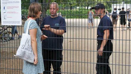 Einlass nur mit Kind: Eine Frau spricht mit Sicherheitspersonal am Eingang zum Freibad in Pankow.
