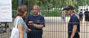 Einlass nur mit Kind: Eine Frau spricht mit Sicherheitspersonal am Eingang zum Freibad in Pankow.