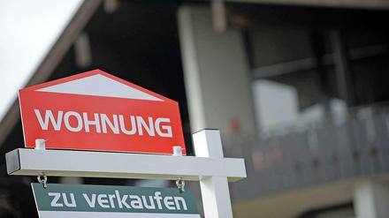 Ein Schild "Wohnung zu verkaufen" vor einem Haus.