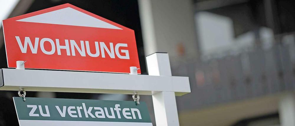Ein Schild "Wohnung zu verkaufen" vor einem Haus.