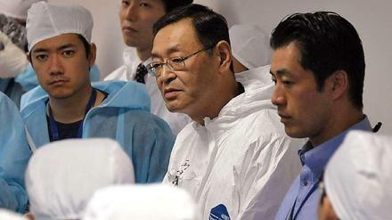 drei Männer in Schutzkleidung, in der Mitte Yoshida