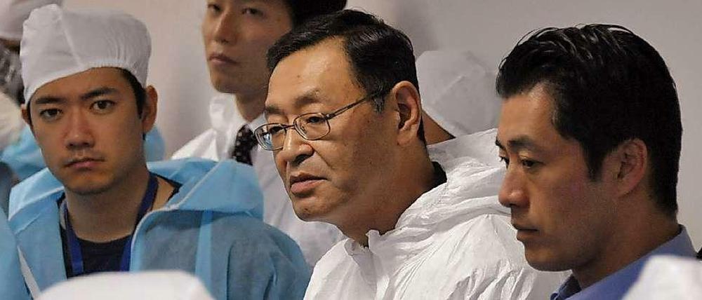 drei Männer in Schutzkleidung, in der Mitte Yoshida