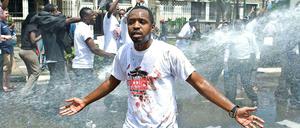 Mann mit ausgebreiteten Armen wird von Wasserwerfer attackiert